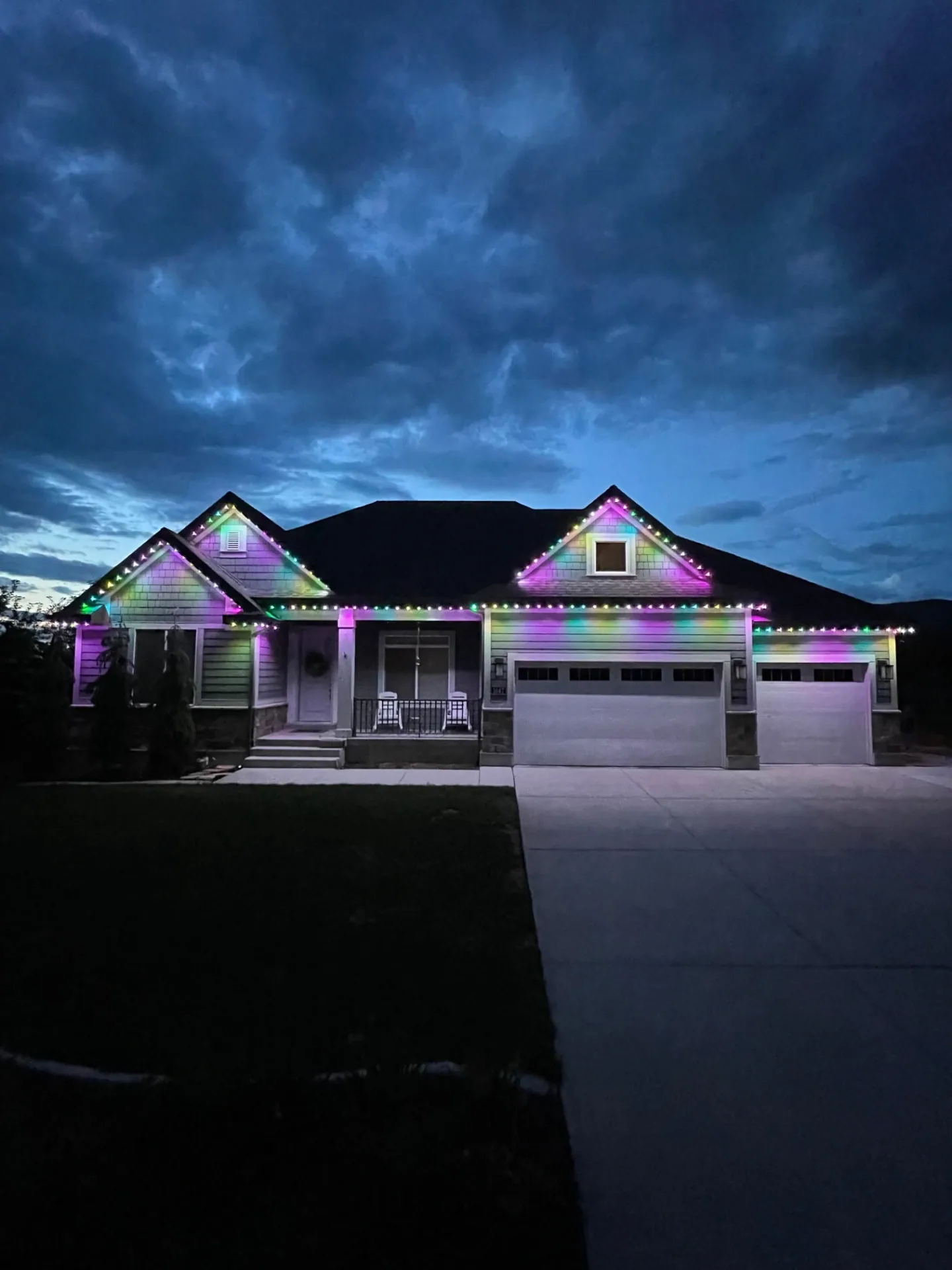 Home at dusk with multicolor lights along the gables