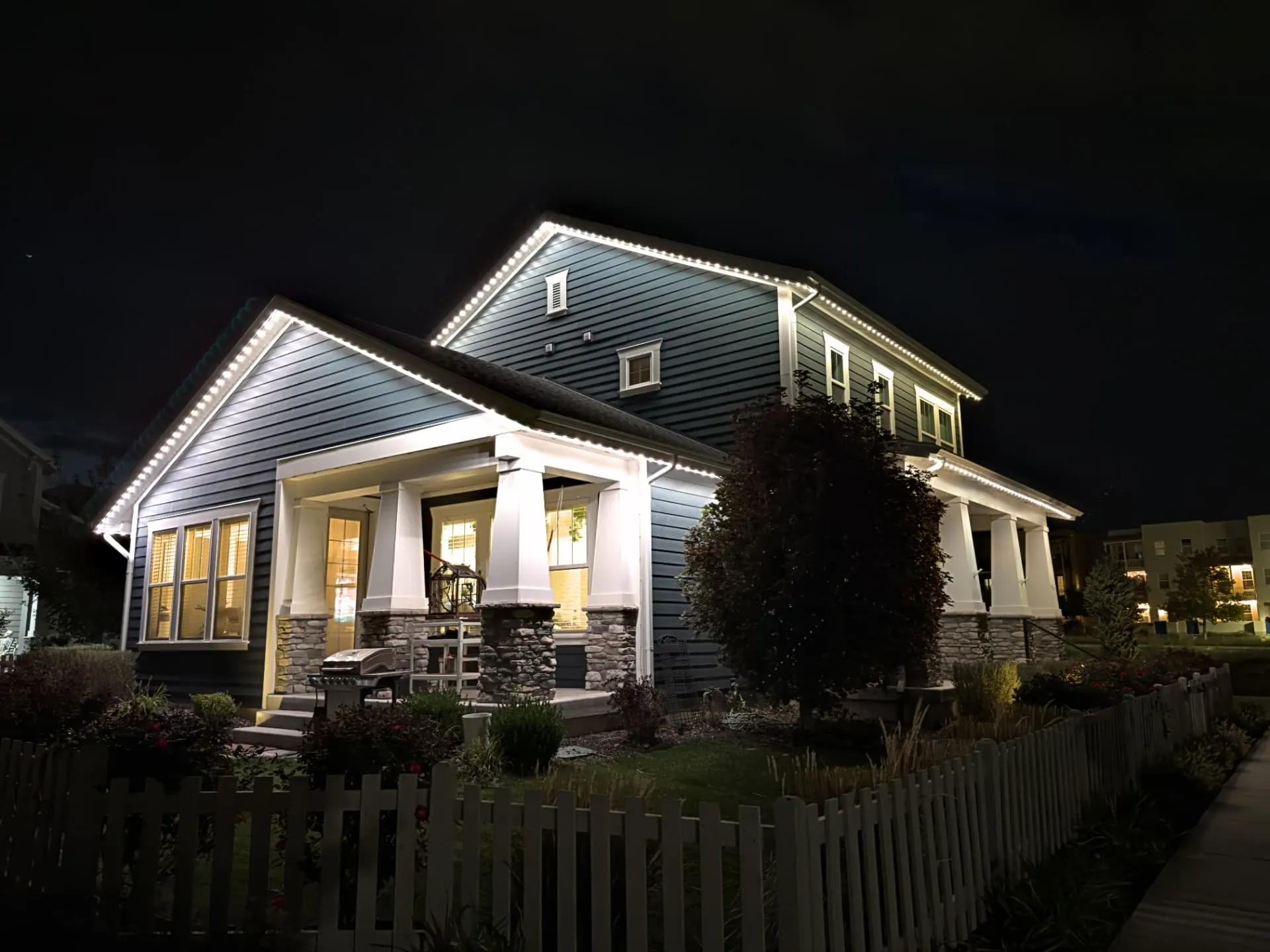 Home at night with crisp white permanent roofline lighting along the gables