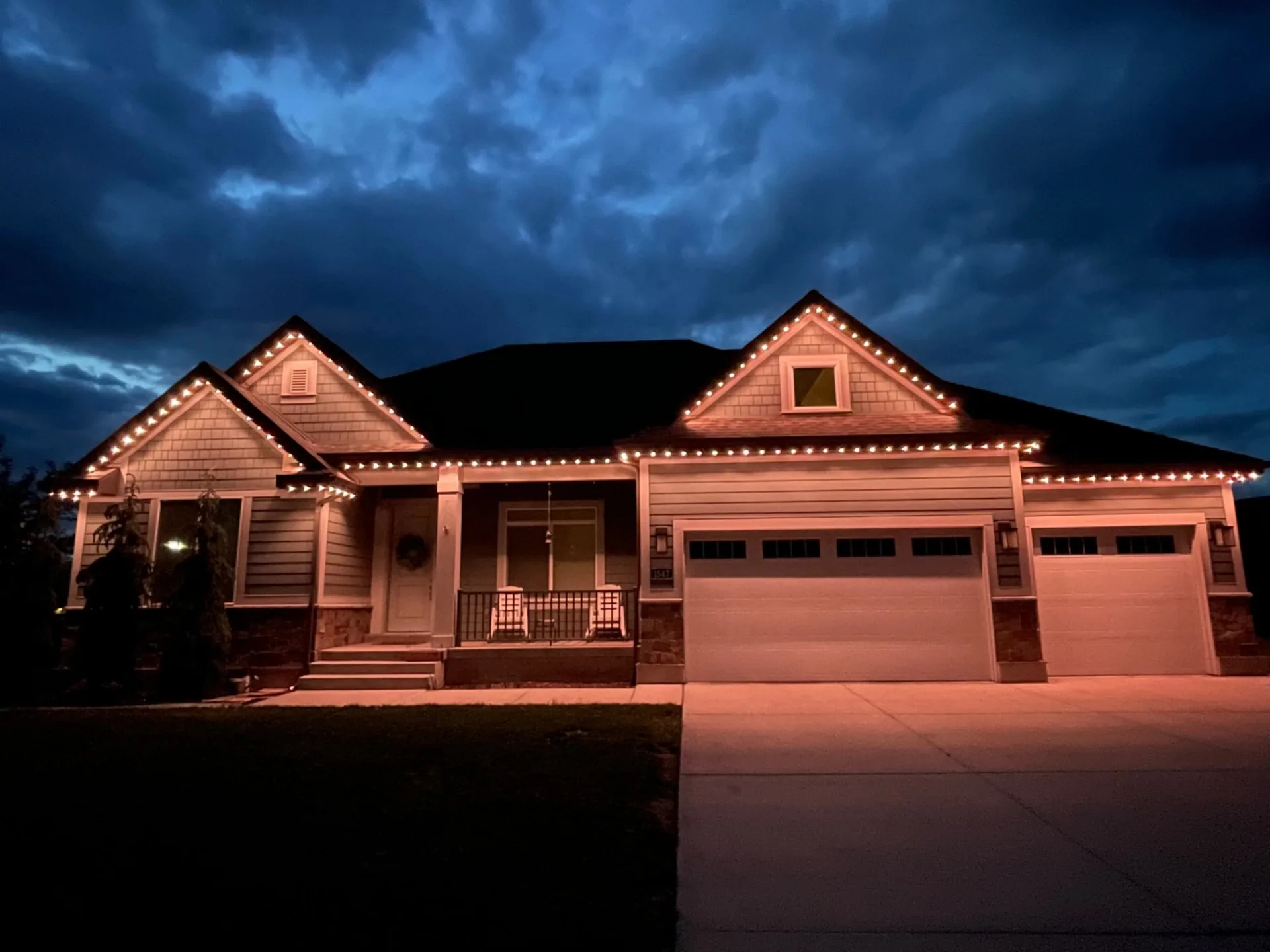 Craftsman home at dusk with warm white lights along the roofline