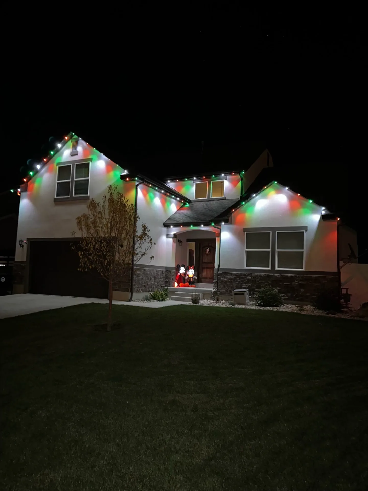 Two-story home with red, green and white Christmas lighting