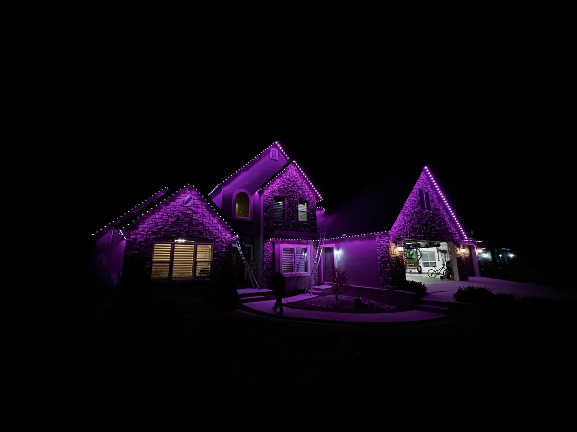 Stone home lit in purple during installation